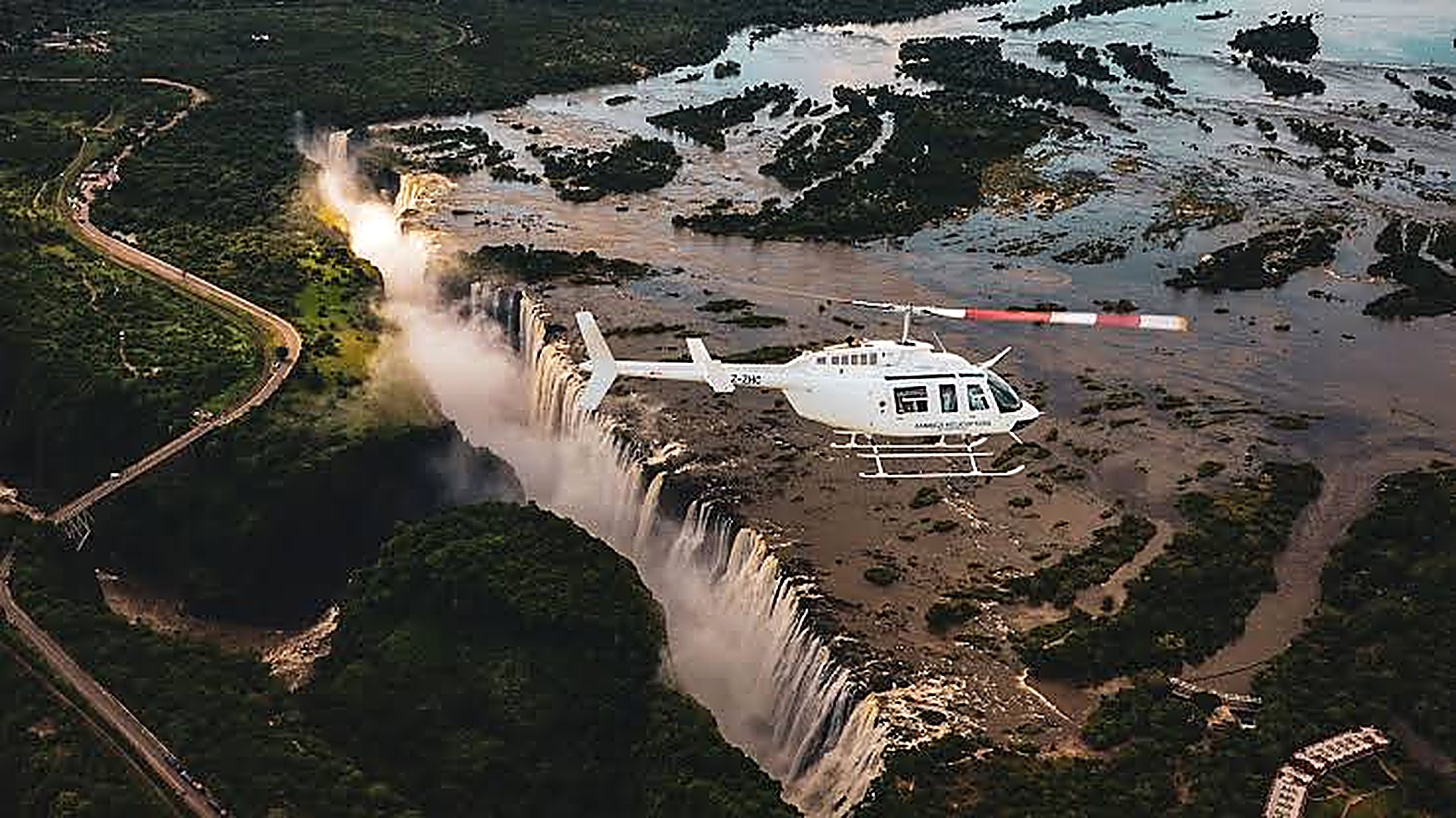 Helicopter flying above Victoria Falls and the misty Zambezi gorge